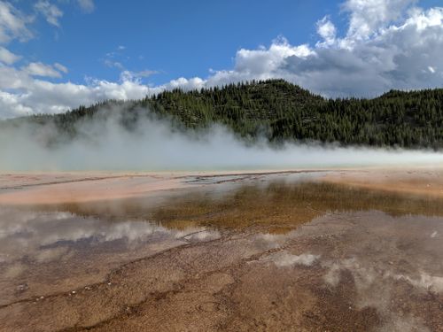 Free Beautiful misty scene at Yellowstone's Grand Prismatic Spring with vibrant reflections and surrounding forest. Stock Photo