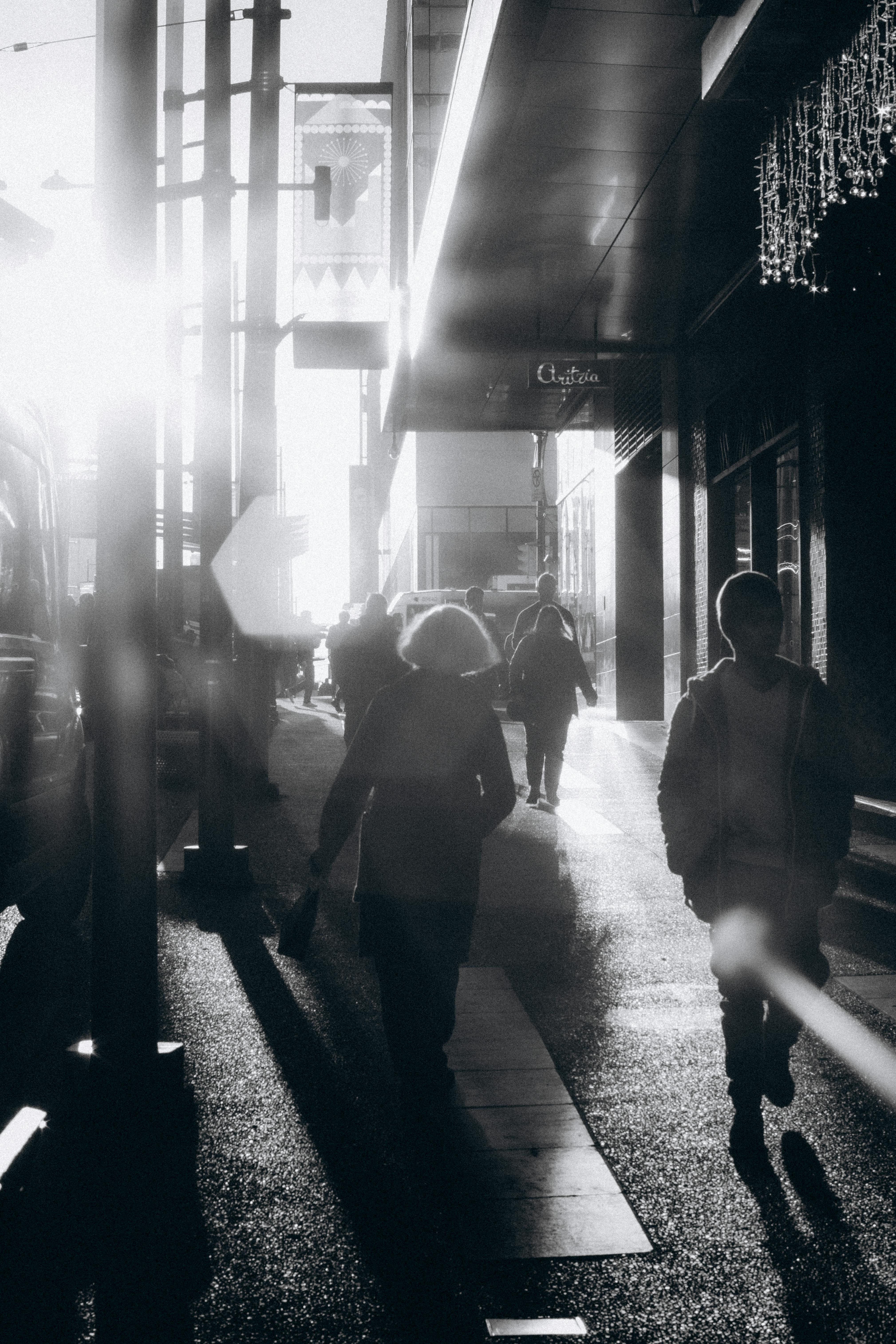 Sunlit silhouettes of people walking on a city street during sunset, capturing urban life.