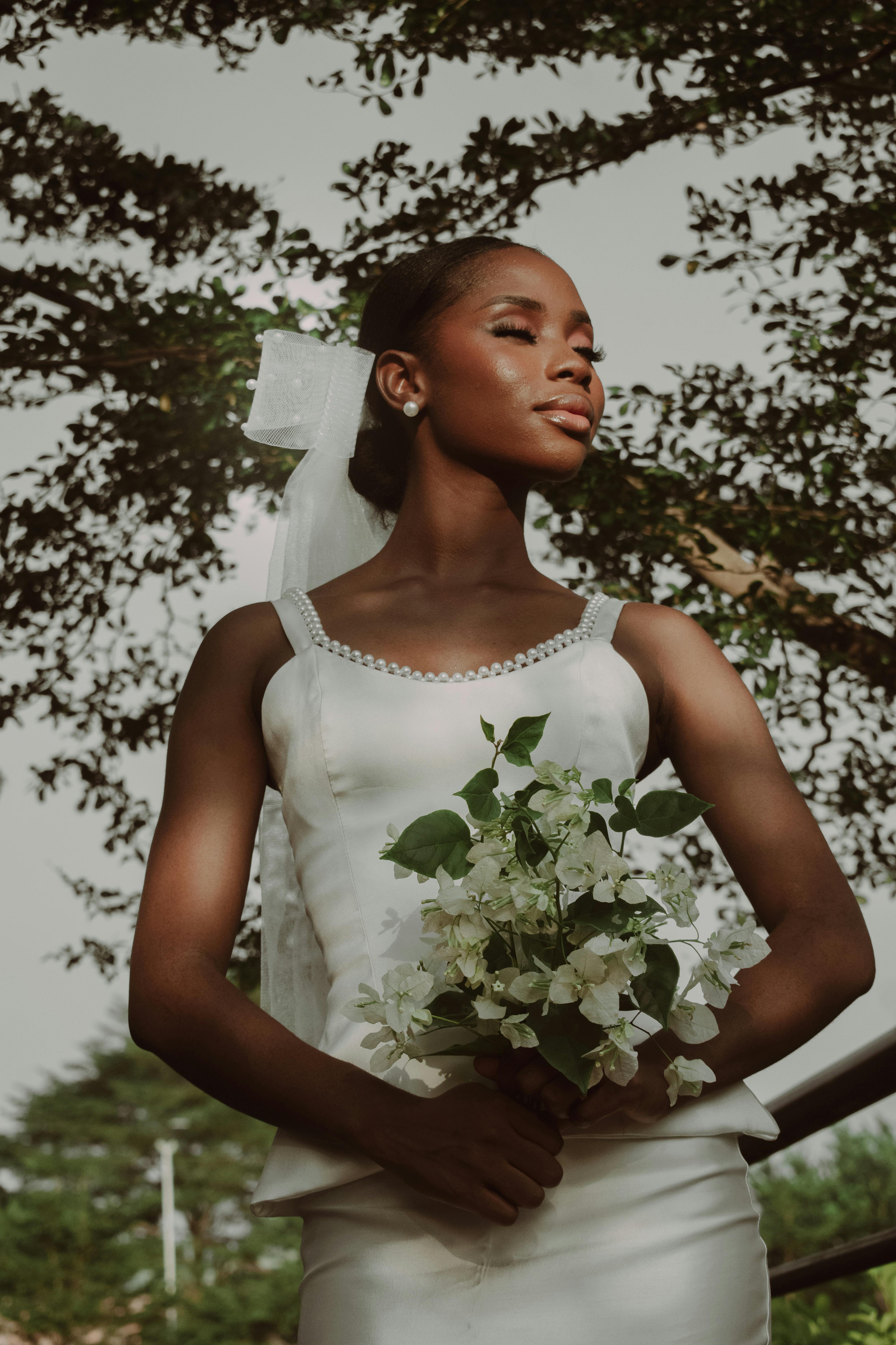 Stunning bride in a white dress holding a bouquet, captured in a serene garden.