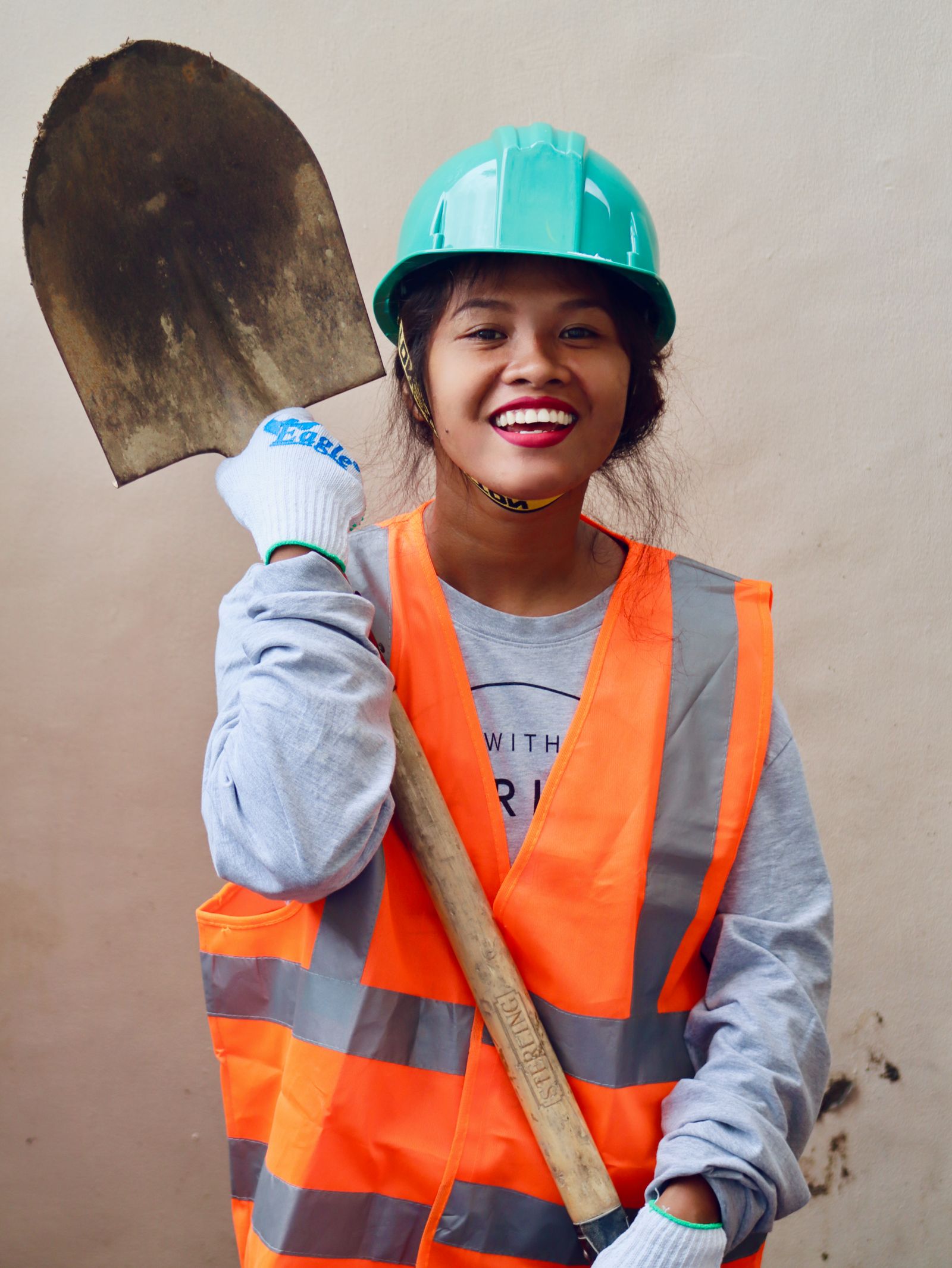 Smiling female construction worker in safety gear holding a shovel in Caraga