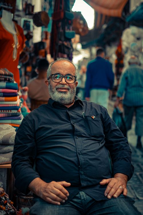 Free Portrait of a seated man in the bustling market of Tunis, offering a glimpse into daily life. Stock Photo