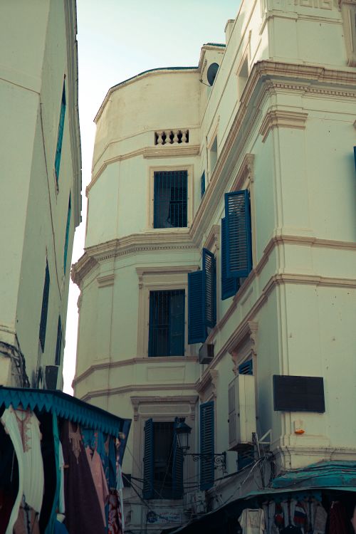 Free Vintage colonial buildings with blue shutters in a narrow alley evoke historic charm. Stock Photo