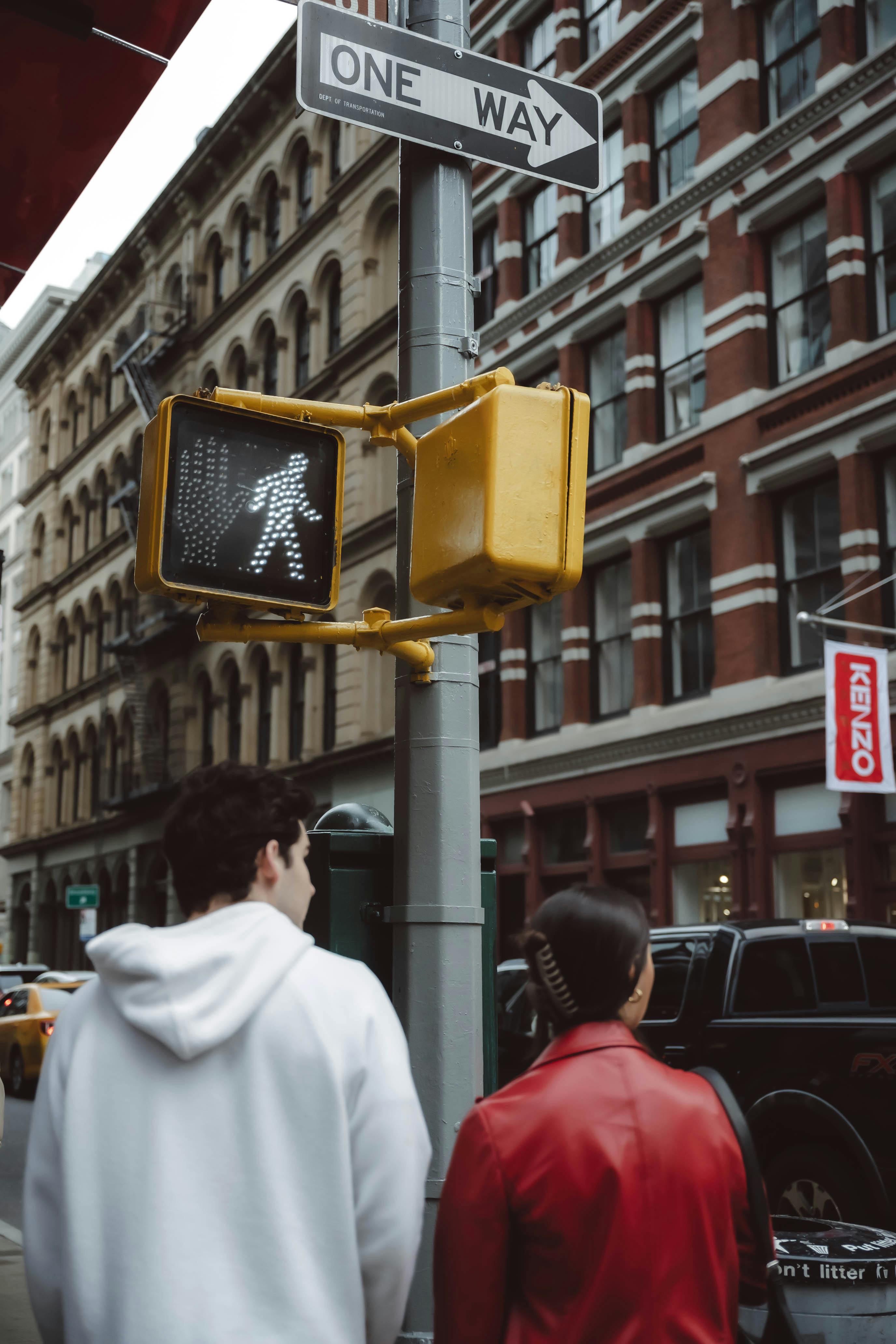 A bustling New York City street with people crossing at a pedestrian signal.