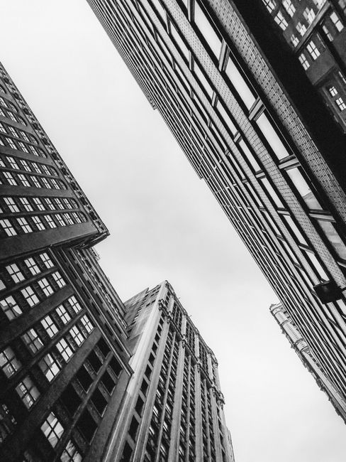 Black and white view of New York City skyscrapers from street level, capturing urban architecture.