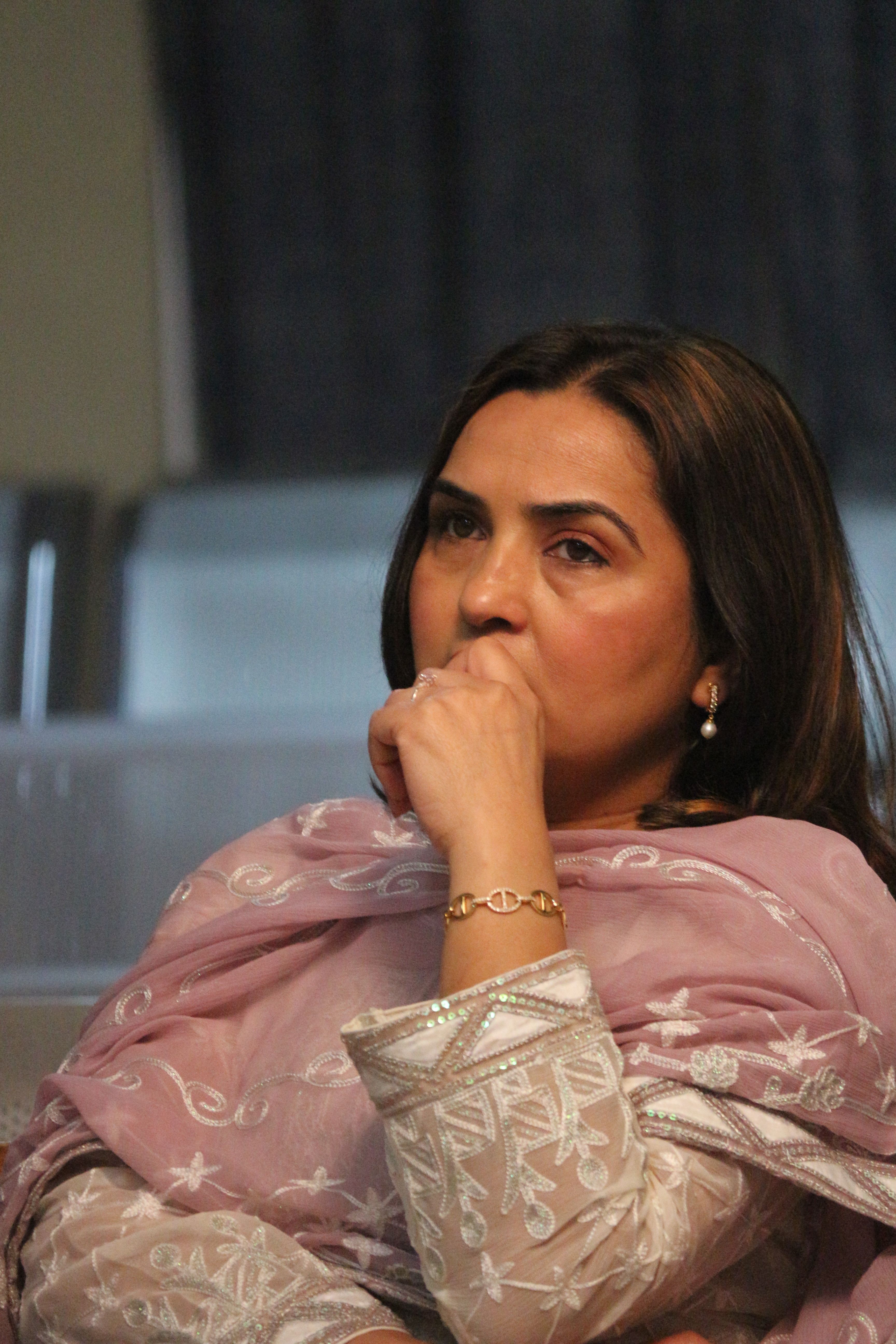 Woman in pink traditional outfit pondering, conveying contemplation.