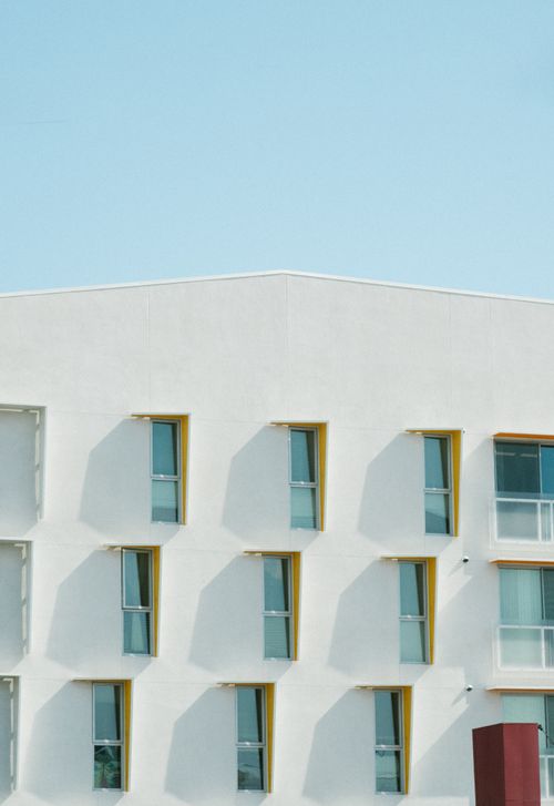 Free Minimalist apartment facade with geometric window patterns against clear sky. Stock Photo