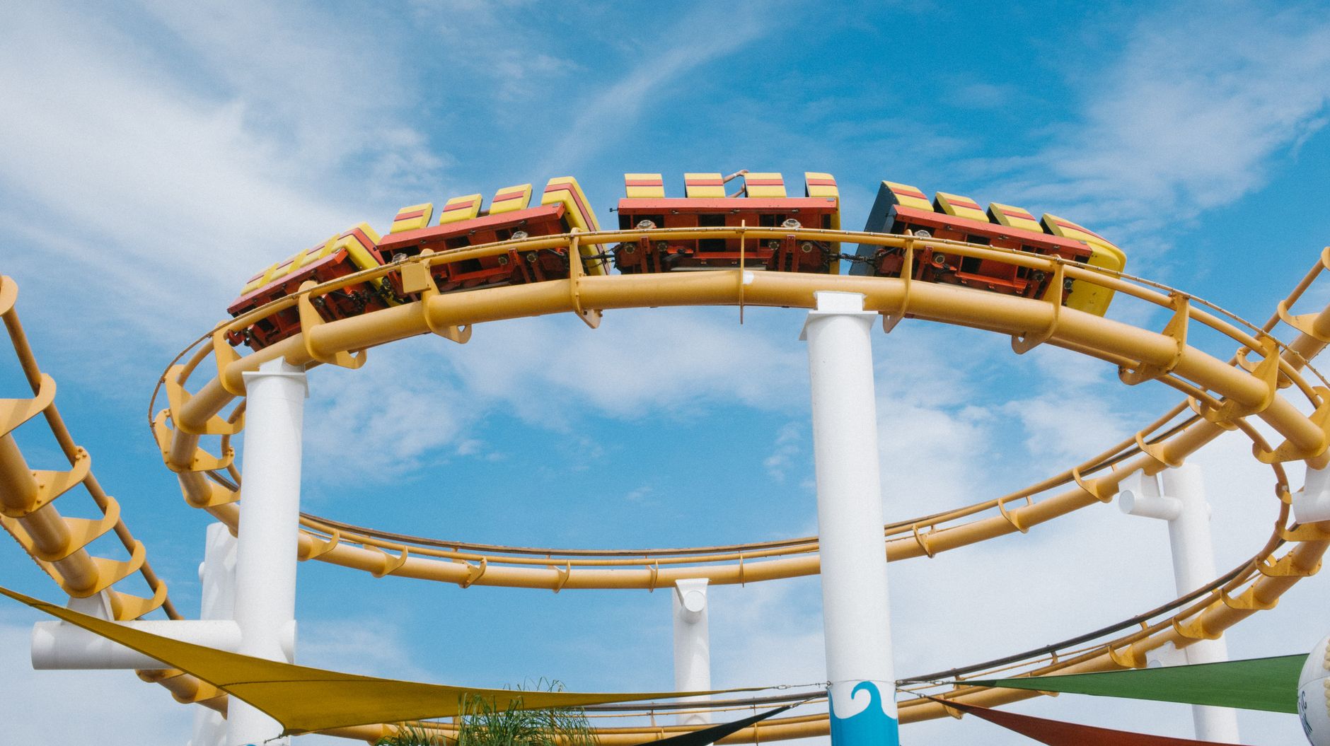 A vibrant roller coaster loop at an amusement park set against a clear blue sky, evoking thrill and excitement.