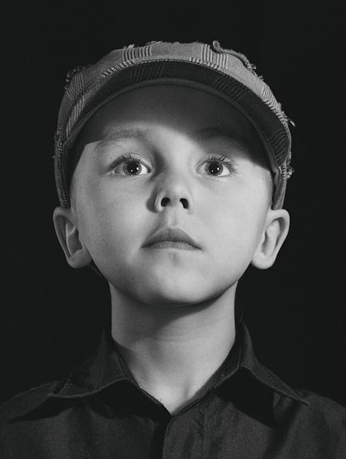 Greyscale Photography of Boy Wearing Hat