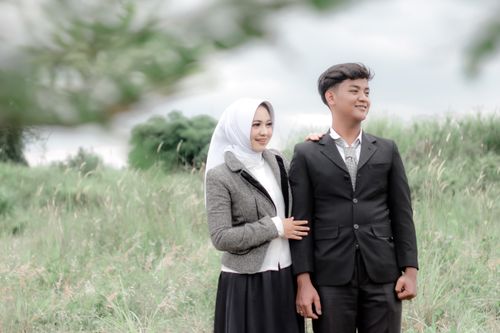 Free Portrait of a smiling couple in nature, wearing formal attire, serene atmosphere. Stock Photo