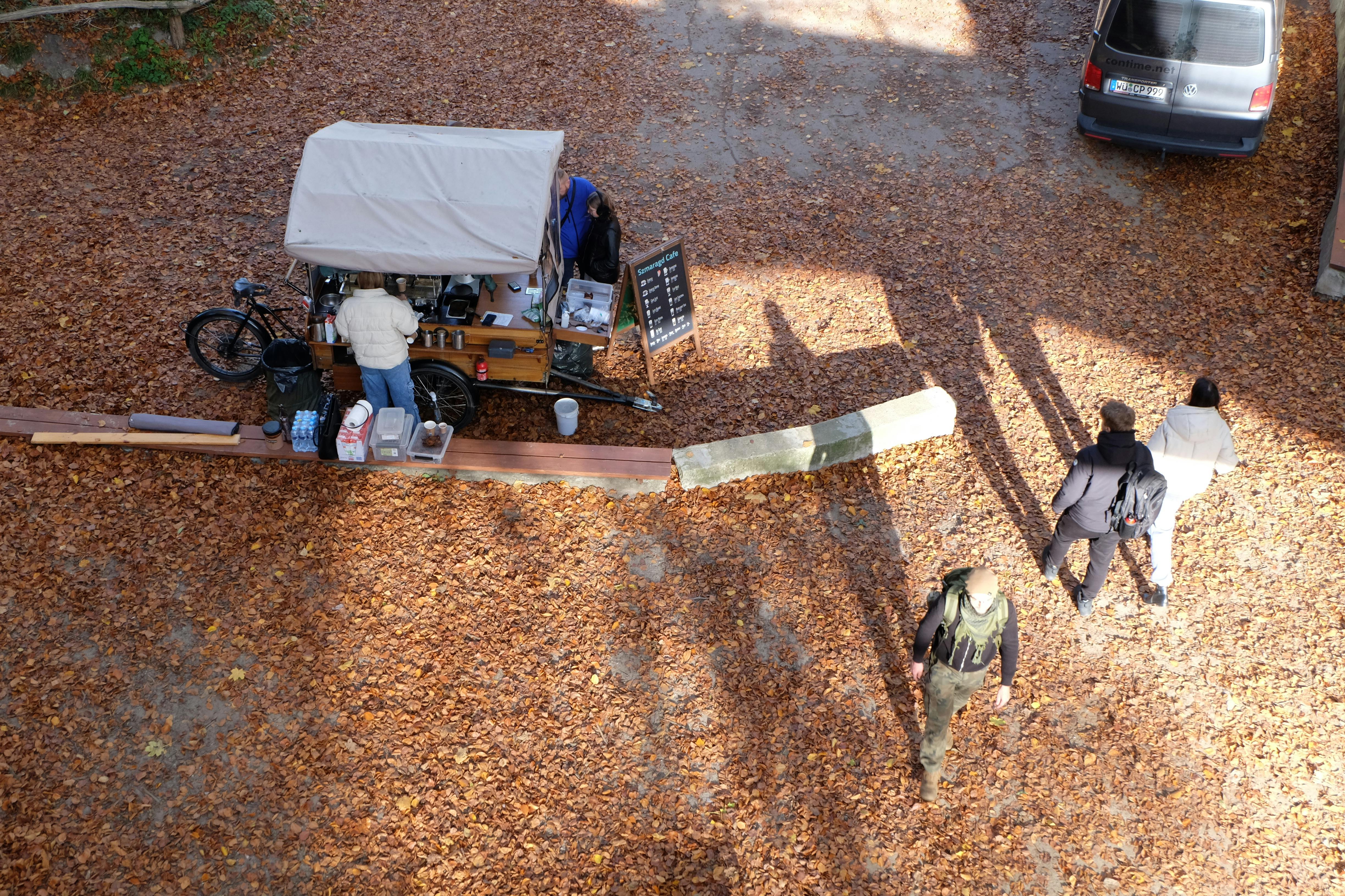 gratis Luchtfoto van een koffiekarretje op een met bladeren bedekte straat, met voorbijgangers in de herfst. Stockfoto
