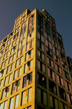 Capture of a modern high-rise building with warm sunset reflections on its windows.