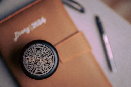 Free Close-up of a desk with a 2024 diary, speaker, and pen, creating a modern workspace vibe. Stock Photo