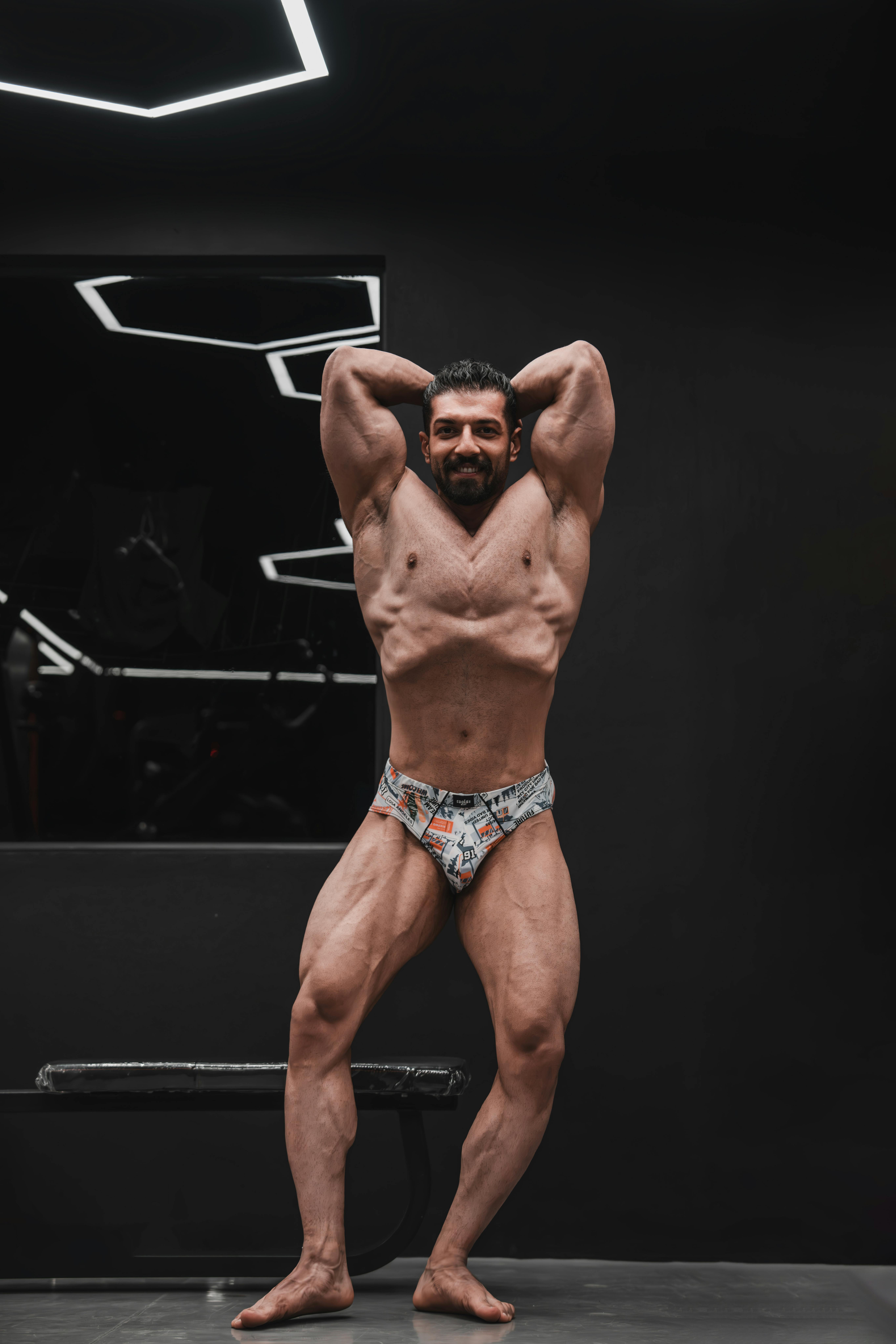 Bodybuilder showcasing defined muscles in a sleek indoor gym.