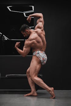 Muscular male bodybuilder posing indoors in a modern gym, showcasing strength
