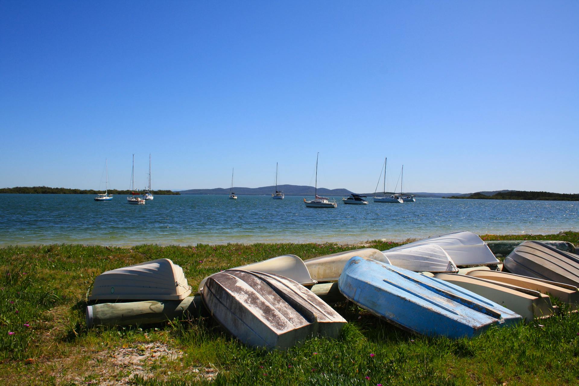 Anchored boats and upturned dinghies by the serene Taylors Beach, Australia.