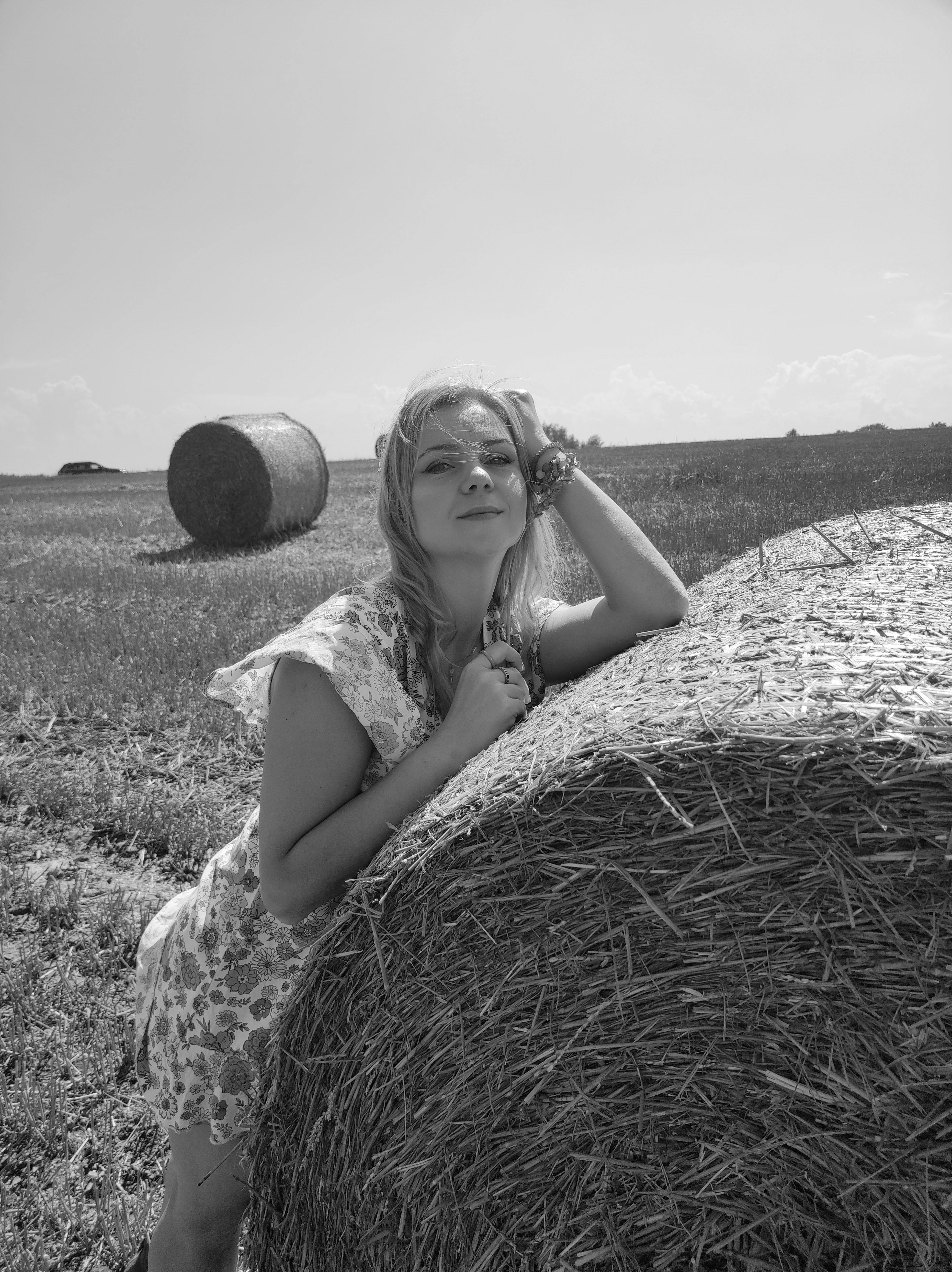 woman relaxing by hay bale in countryside