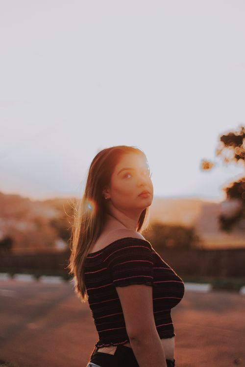 Free A young woman with brown hair looks upward during a serene summer sunset. Stock Photo