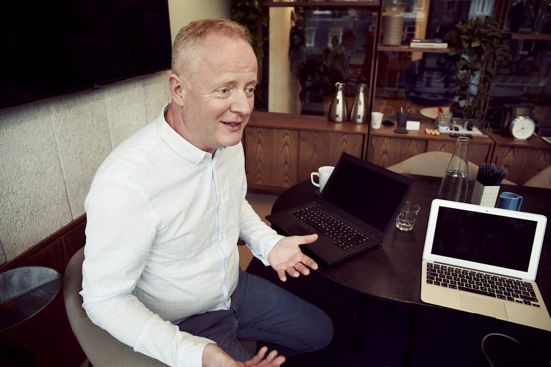 Man Wearing Long Sleeved Shirt Sitting Beside Table