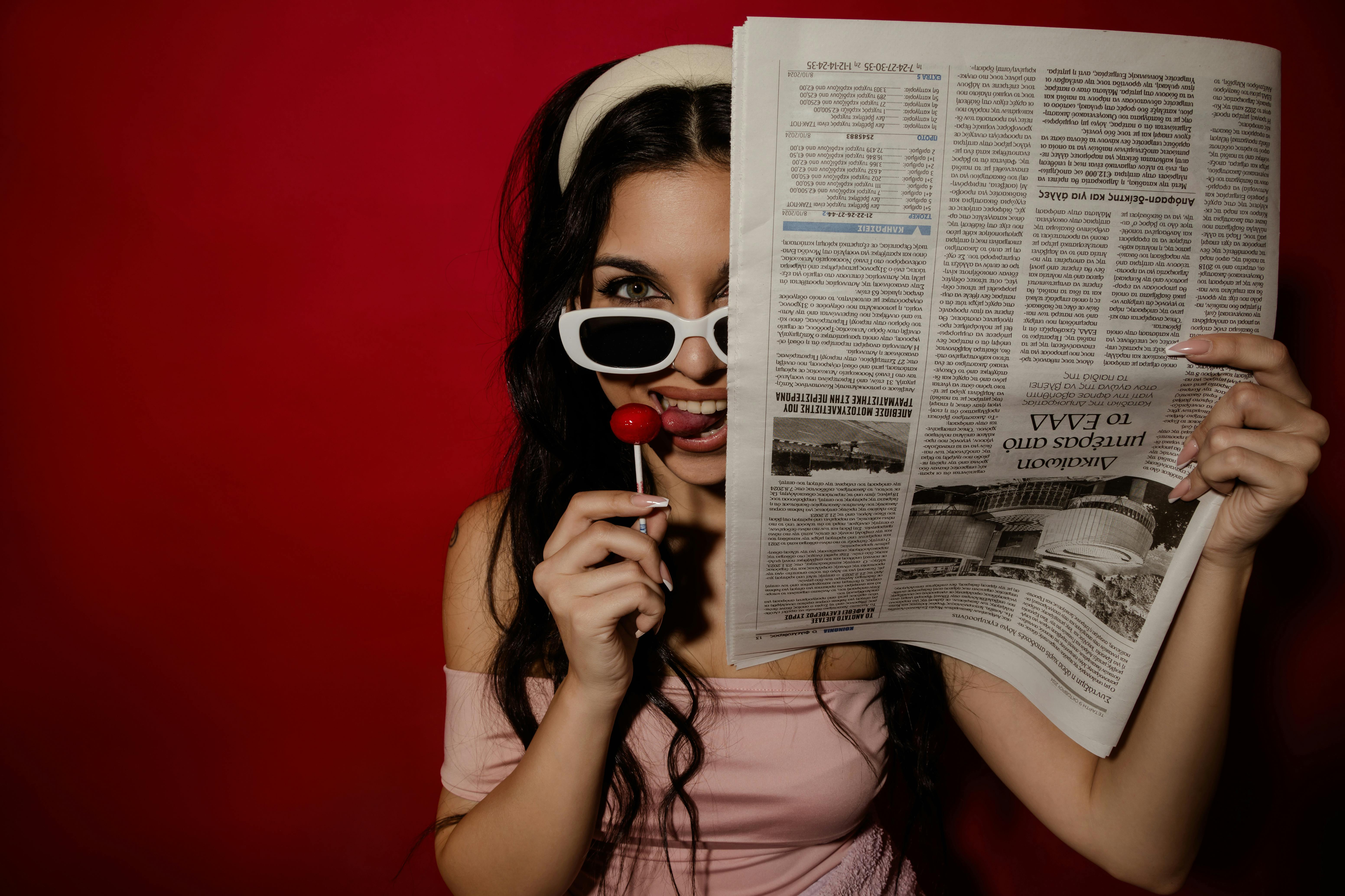 stylish woman reading newspaper with lollipop