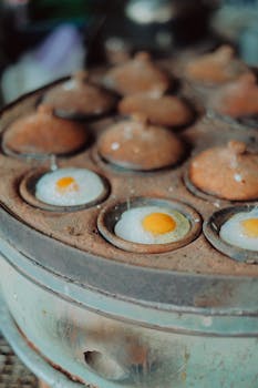 Close-up of quail eggs cooking in a traditional Vietnamese street food setting.