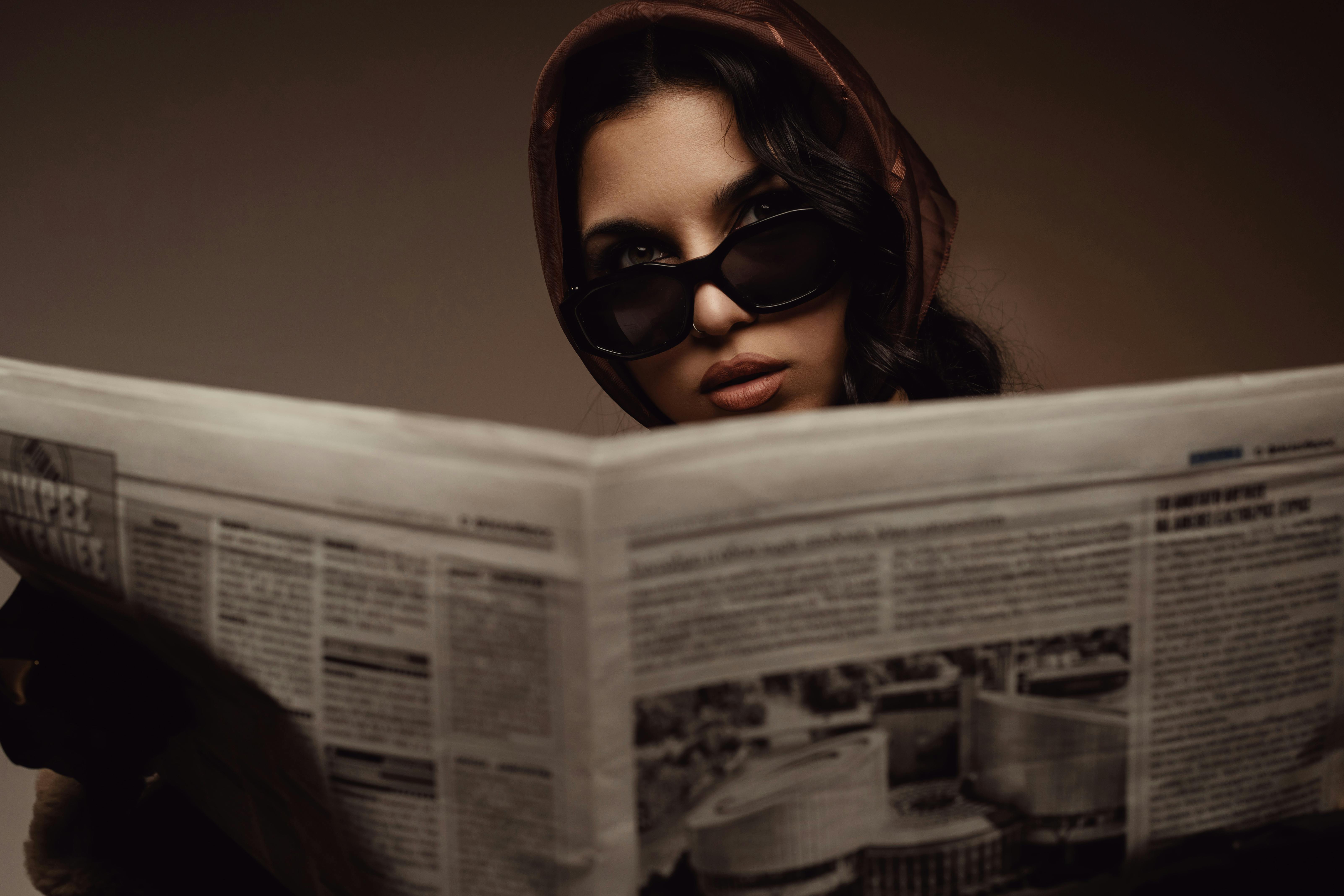 stylish woman reading newspaper in sunglasses