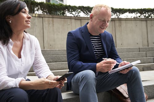 Free Woman and Man Having a Discussion While Sitting on Steps Stock Photo