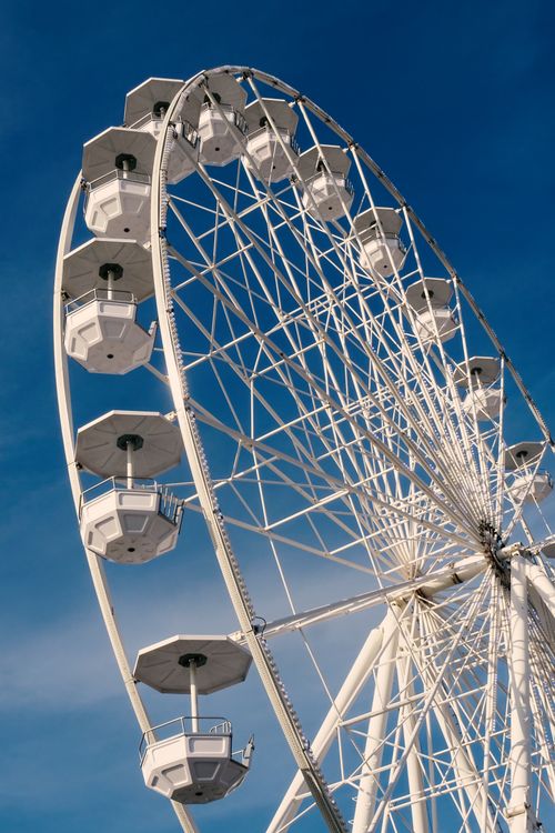 Free Close-up view of a giant Ferris wheel with white cabins against a clear blue sky. Stock Photo