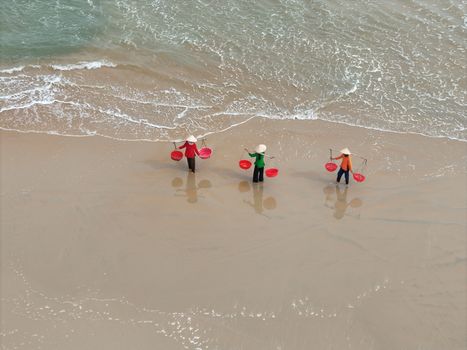 Aerial view of Vietnamese fishermen with conical hats on Hoi An beach, Vietnam.
