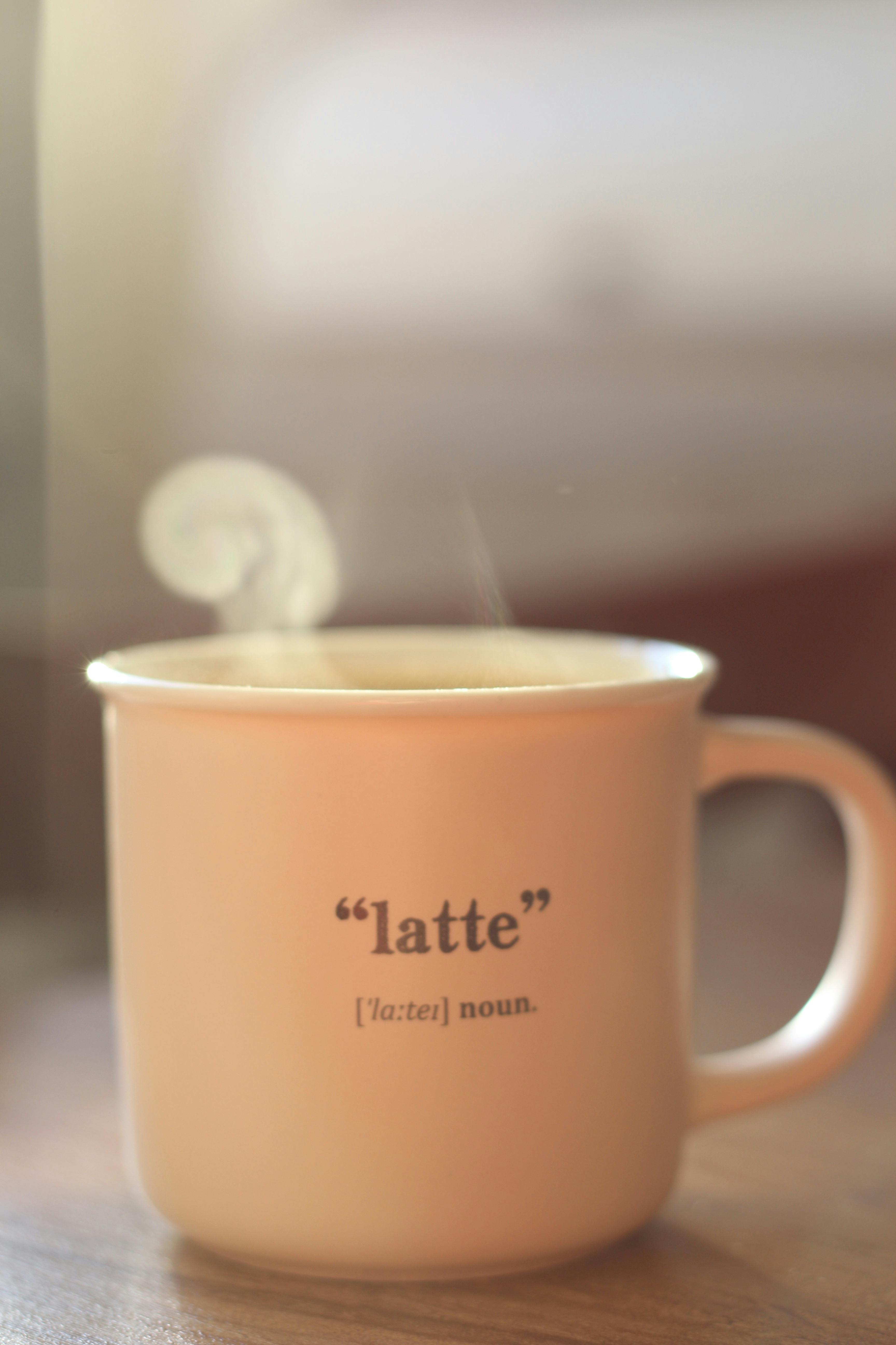 A warm latte mug releasing steam, with a soft focus background and cozy ambiance.