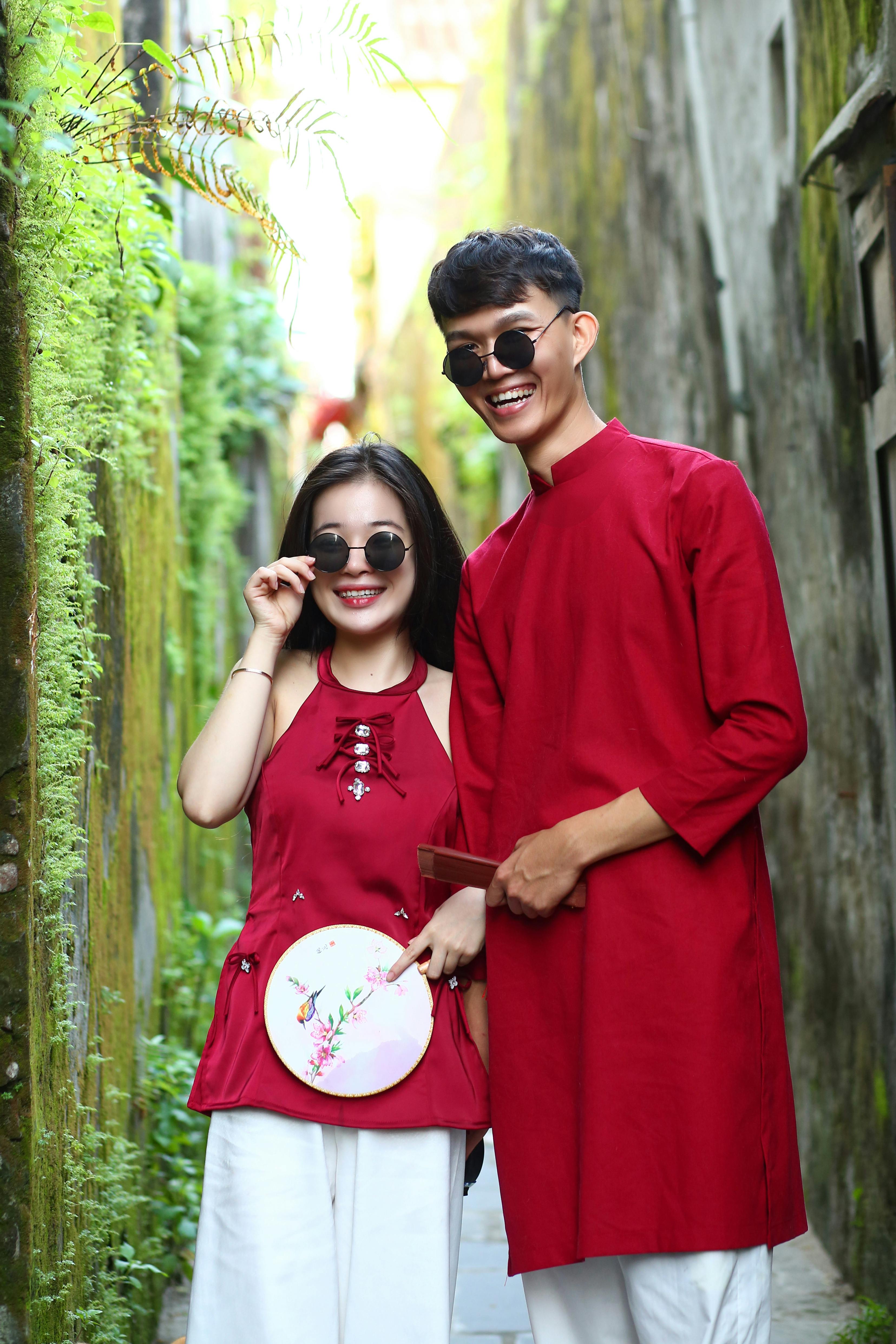 Young couple in vibrant red ao dai posing in the streets of Hội An, Vietnam.