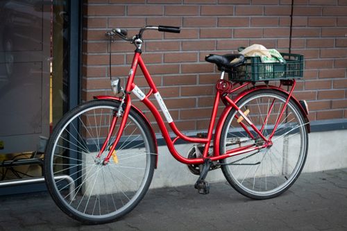 Free A vibrant red bicycle with basket parked near a brick wall in Druskininkai, Lithuania. Stock Photo