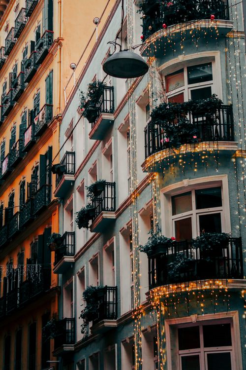 Free Colorful European building adorned with decorative lights and balcony plants, perfect for festive visuals. Stock Photo