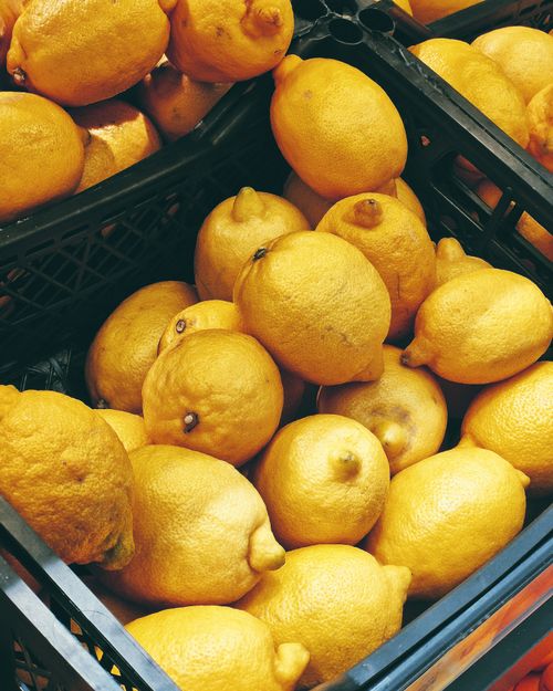 Free A vibrant display of fresh lemons in black crates at a market, emphasizing their bright yellow color. Stock Photo