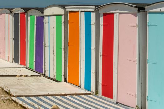 Vibrant beach huts in Le Havre, France, showcasing a rainbow of colors in sunny weather.