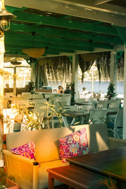 Charming cafe with colorful decor overlooking a tranquil waterfront, perfect for relaxation.