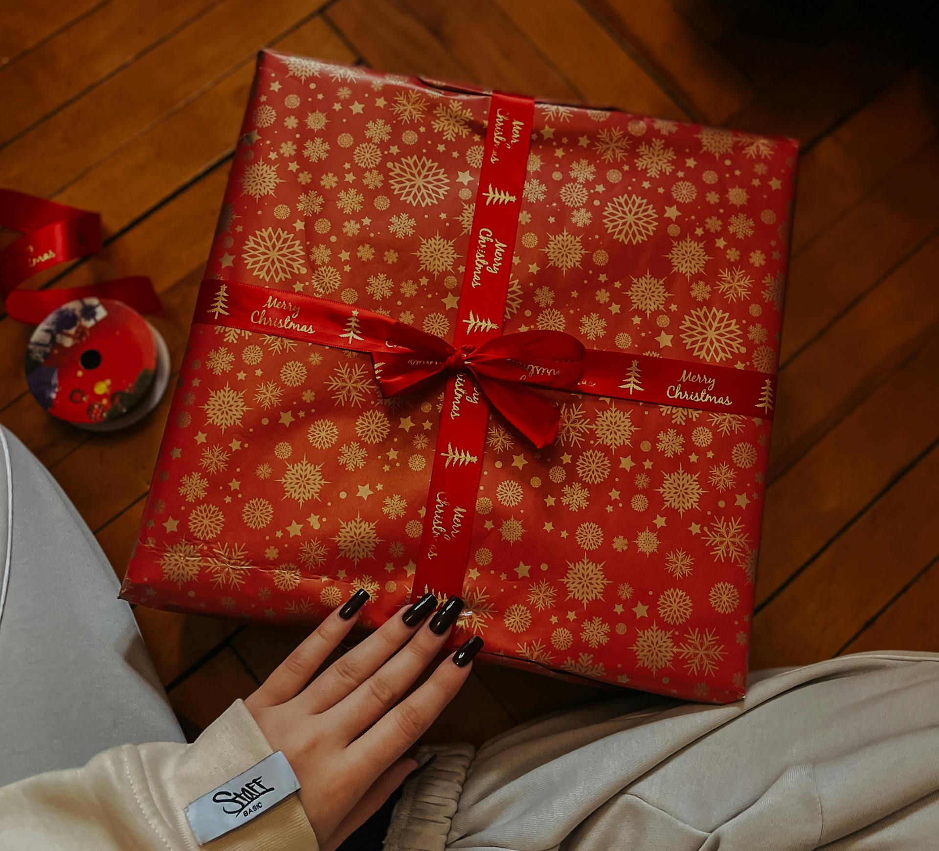 A beautifully wrapped Christmas gift with red paper and festive decorations, capturing the holiday spirit.
