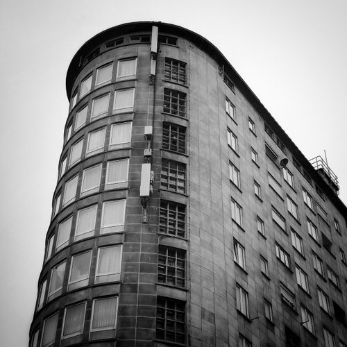 Free Black and white photo of a modern curved building with numerous windows. Stock Photo