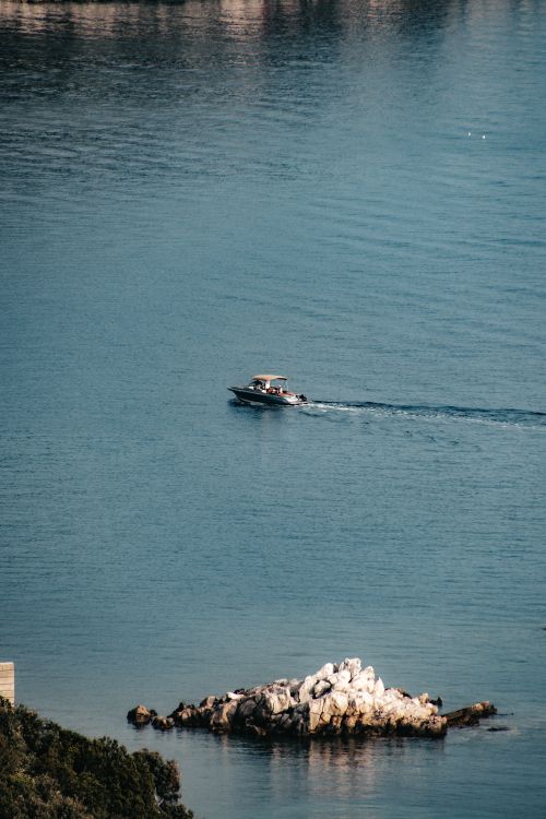 Free A tranquil boat gliding over the Adriatic Sea near Lopud island in Croatia, capturing summer's essence. Stock Photo