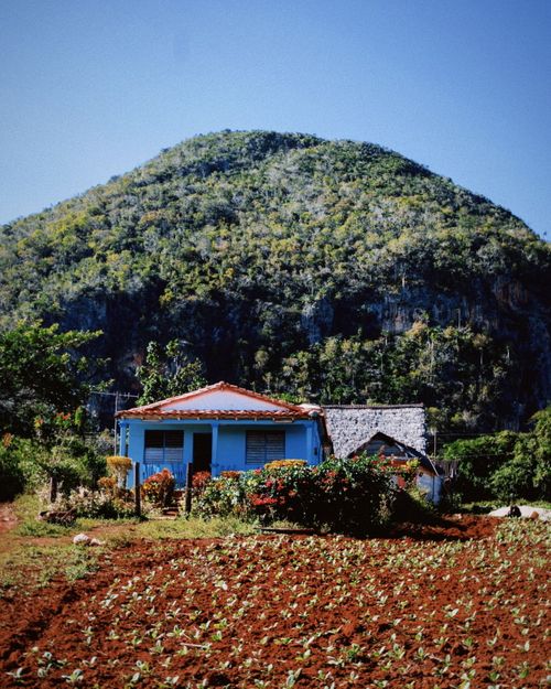 Free Rustic blue house in picturesque rural landscape with lush green mountain. Stock Photo