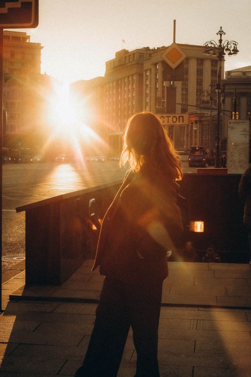 Free A striking silhouette of a person with sun flare in a city during sunset. Stock Photo