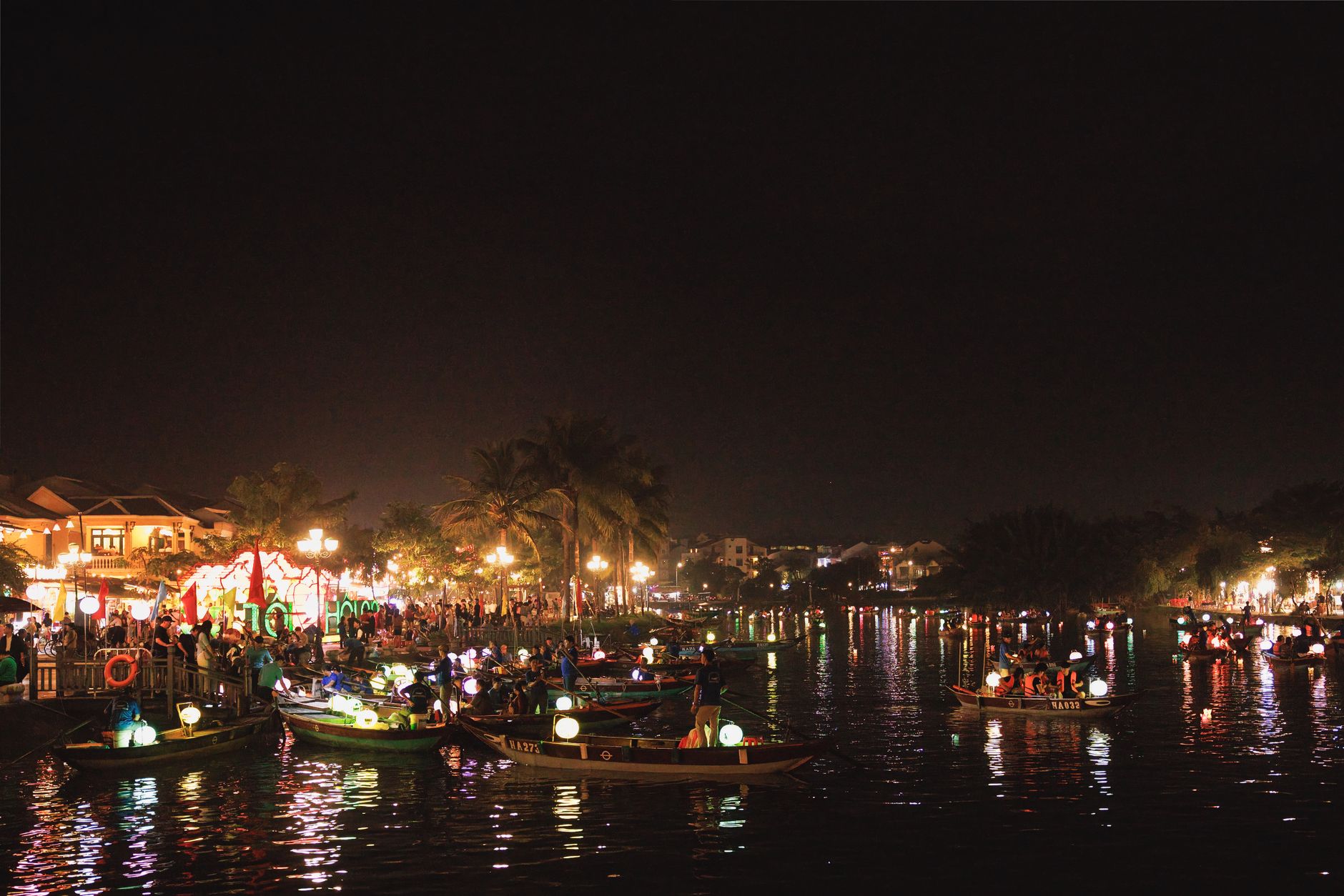 Vibrant night scene showcasing bustling riverside festivities in Hoi An Ancient Town, Vietnam.