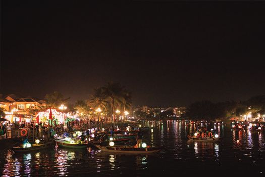 Vibrant night scene showcasing bustling riverside festivities in Hoi An Ancient Town, Vietnam.