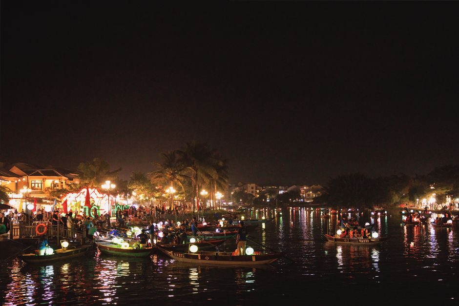 Vibrant night scene showcasing bustling riverside festivities in Hoi An Ancient Town, Vietnam.