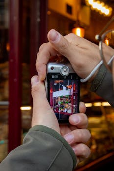 Capture of hands holding a camera displaying a vibrant cafe scene.