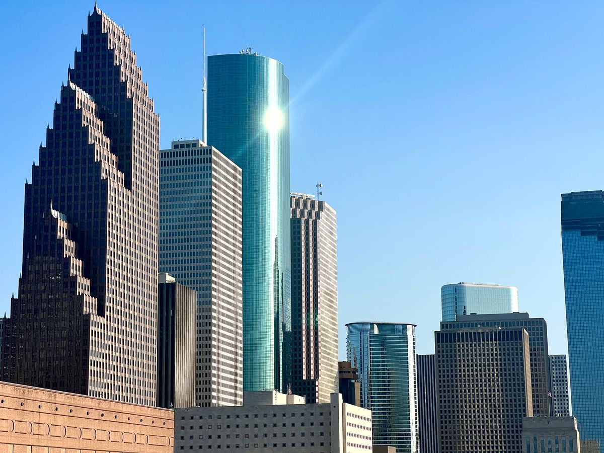 Downtown Houston skyscrapers under a clear blue sky, the view that greets people moving to Houston, Texas