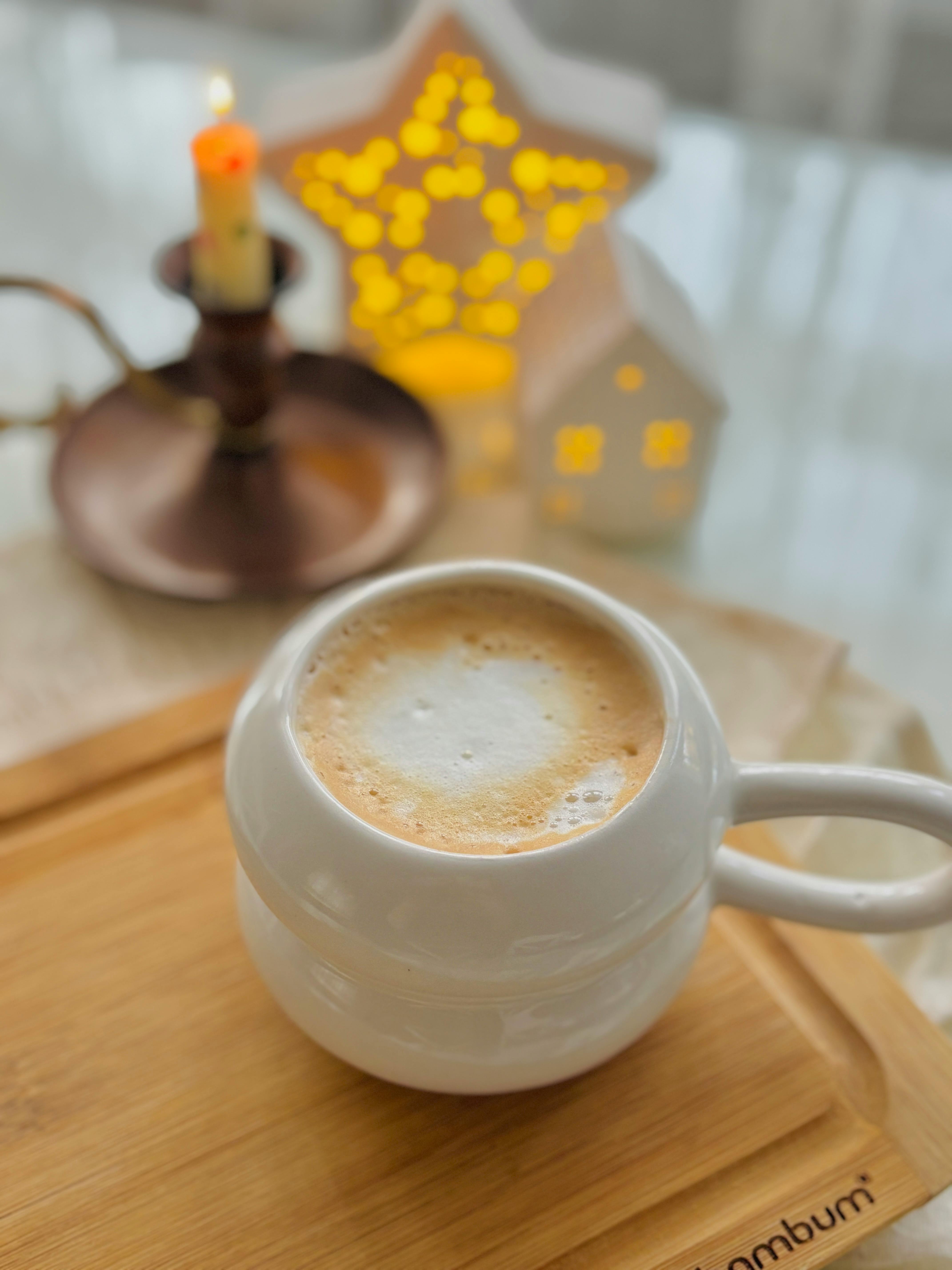 Warm and cozy latte setup with candle and star-shaped decor on a wooden tray.
