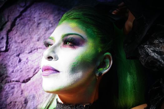 A striking portrait with vibrant face makeup and dramatic lighting.