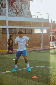 Young male athlete practices soccer skills on outdoor field during daylight.