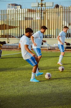 Three young soccer players practicing with footballs on a sunny day.