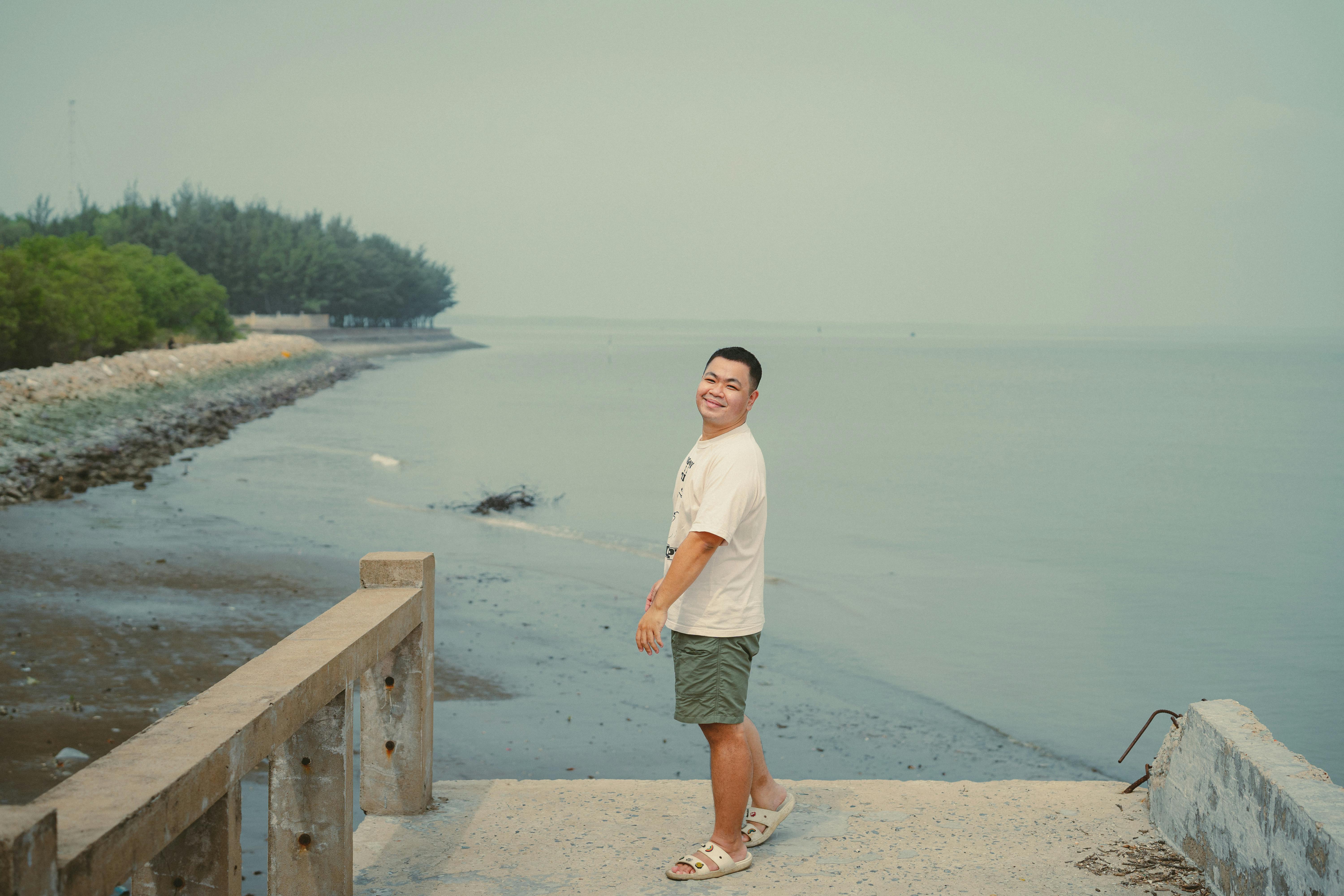 man standing on pier overlooking ho chi minh city coastline